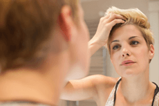 Frau prüft ihre Haare im Spiegel